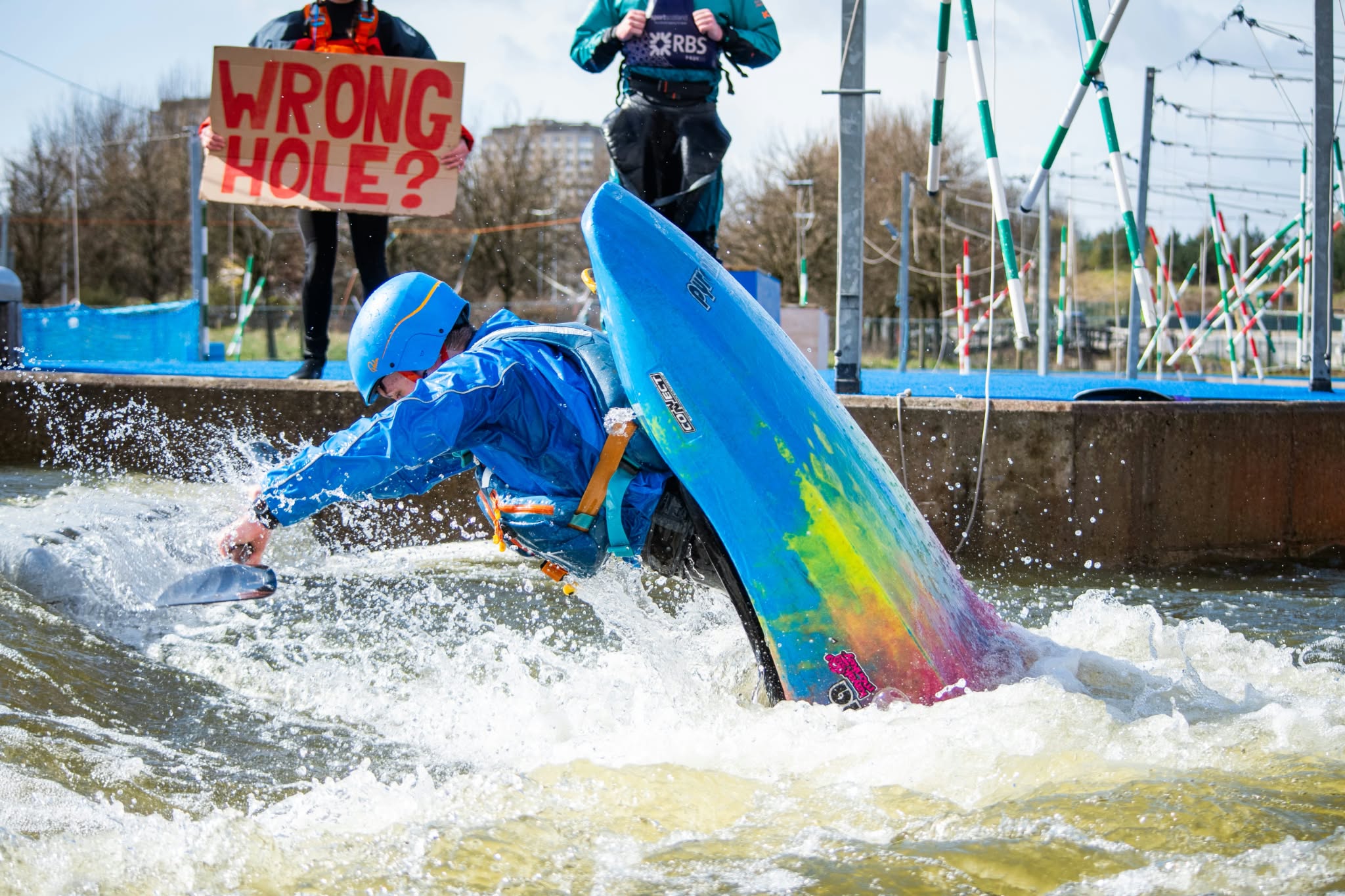 Freestyle kayaker performing a vertical move in a blue boat at Pinkston Watersports in Glasgow